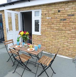 a wooden table with chairs and flowers on a patio at 2 BED TERRACED FLAT PICCADILLY LINE in London