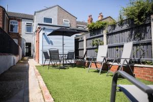 a patio with chairs and an umbrella on the grass at Unique and Stylish close to Beaches Restaurants Shops in Cleethorpes