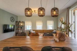 a living room with a large wooden table and chandeliers at Hello Zeeland - vakantiewoning Knuitershoek 86 in Kloosterzande