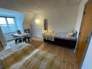 een slaapkamer met 2 bedden, een tafel en een bureau bij Room 17 - Hawkraft kulturhotel in Vestervig