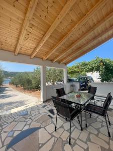 eine Terrasse mit einem Tisch und Stühlen unter einem Holzdach in der Unterkunft Beachfront Holiday House Melissa in Vinišće