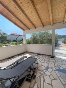 eine überdachte Terrasse mit einer Bank und einem Tisch in der Unterkunft Beachfront Holiday House Melissa in Vinišće