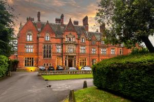 a large brick building with cars parked in front of it at WA Hotel (Wroxall Abbey) in Wroxall