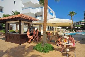 un grupo de personas sentadas en un bar en un complejo en Petrosana Hotel Apartments, en Ayia Napa