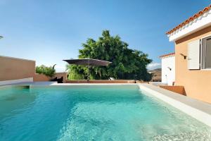 a swimming pool in front of a house with an umbrella at Los Corcos Rural Farm With Private Pool in Playa de San Juan