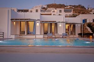 a villa with a swimming pool in front of a house at Aqua Breeze Seaview Pool Suites Mykonos in Mýkonos City