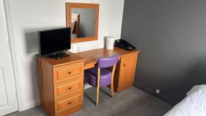 a bedroom with a desk with a tv and a purple chair at The Strathmore Hotel in Morecambe