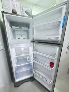 um frigorífico vazio com a porta aberta numa cozinha em Apartamento vista mar na Praia Grande
