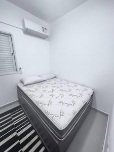 uma cama sentada num quarto ao lado de uma janela em Apartamento vista mar na Praia Grande