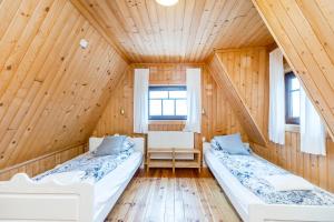 2 łóżka w pokoju z drewnianymi ścianami w obiekcie Łobrotno Gaździna - góralska chałupa na wyłaczność w Bukowinie Tatrzańskiej