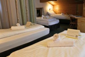 ein Hotelzimmer mit 3 Betten und einem Schreibtisch in der Unterkunft Gasthof Alpensport in Saalbach-Hinterglemm
