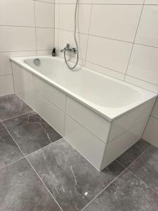 a white bath tub in a bathroom with tile walls at Meine gemütliche Auszeit in Wolfsburg +9 photos