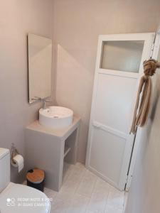 a white bathroom with a sink and a mirror at Vlastos 1 in Ios Chora