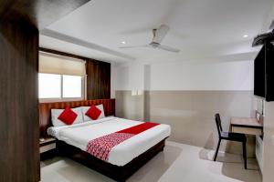Schlafzimmer mit einem Bett mit roten Kissen und einem Schreibtisch in der Unterkunft Super OYO Flagship Hotel Everest Lodging Vashi in Mumbai