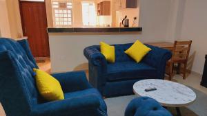 ein Wohnzimmer mit 2 blauen Sofas und einem Tisch in der Unterkunft MaGiK Furnished All Ensuite 2 bedroom Apartment in Nyeri
