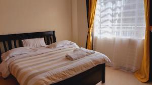 ein Bett mit Handtüchern in einem Zimmer mit Fenster in der Unterkunft MaGiK Furnished All Ensuite 2 bedroom Apartment in Nyeri