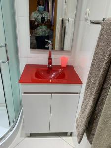 a person taking a picture of a red sink in a bathroom at Paris Hotel in Praia