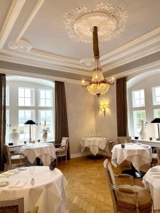 a dining room with tables and a chandelier at Schlosshotel Münchhausen in Aerzen