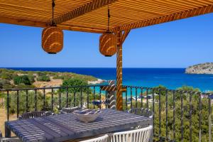 a table on a balcony with a view of the ocean at KALOS LUXURY HOMES, BEACHSIDE EXPERIENCE VOULISMA in Istron