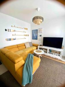 een woonkamer met een bank en een tv bij Les Voiles Blanches T2 luxe à 100m de la plage in Leucate
