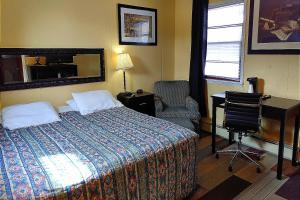 a bedroom with a bed and a desk and a chair at Colonial Inn Extended Stay by OYO New Ulm in New Ulm