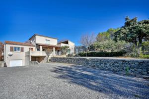 ein Haus mit einer Steinmauer und einer Auffahrt in der Unterkunft Barbouillet - Maison avec piscines partagées in Joyeuse
