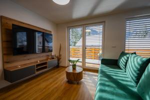 a living room with a green couch and a flat screen tv at Hiša Zima in Gozd Martuljek