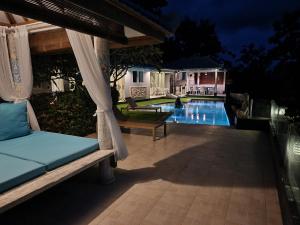 un patio con un columpio y una piscina por la noche en The Kayu Manis Villa, en Lovina