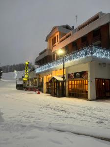 uma rua coberta de neve em frente a um edifício em Hotel Togo Monte Terminillo em Terminillo