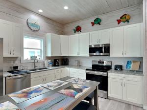 a kitchen with white cabinets and a table at Oasis On The Bay in Rockport