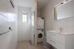 een witte badkamer met een wasmachine en een wastafel bij Hello Zeeland - Vakantiewoning Knuitershoek 88 