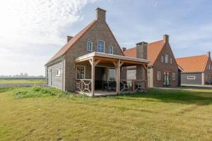 Una gran casa de ladrillo con un porche en un campo en Hello Zeeland - Vakantiewoning Knuitershoek 64, 