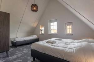 a white bedroom with a bed and a bed sidx sidx sidx sidx at Hello Zeeland - Vakantiewoning Knuitershoek 64 