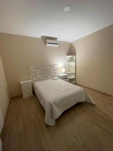 - une chambre avec un grand lit blanc et du parquet dans l'établissement Casa Curutchet, à Cañuelas