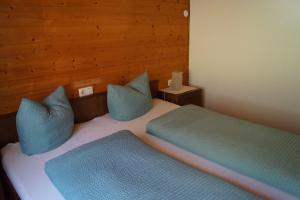 2 Betten in einem Zimmer mit blauen Kissen darauf in der Unterkunft Ferienhaus Lila in Hittisau