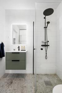 La salle de bains blanche est pourvue d'un lavabo et d'une douche. dans l'établissement Luxurious newly built villa with patio and private parking, à Sigtuna