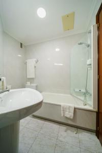 a white bathroom with a tub and a sink at Hotel El Puente in Sanxenxo