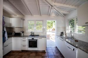 cocina con armarios blancos y fogones en Luxury Vacation Villa 2, en Pointe Milou