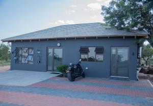 uma casa azul com uma moto estacionada em frente em Boruundi Private Lodge & Campsite em Bokaa
