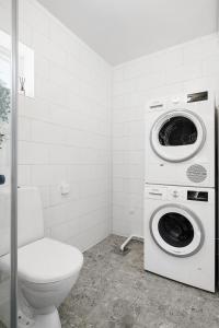 a bathroom with a toilet and a washer and dryer at Luxurious newly built villa with patio and private parking in Sigtuna