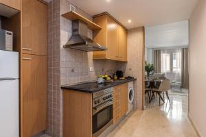 馬德里的住宿－BNBHolder Loving Gran Via Apartment I，厨房配有木制橱柜和炉灶烤箱。