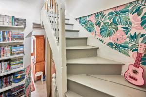 a staircase with a pink guitar next to a book shelf at Cottage Côté Mer - A 1km de la plage in Courseulles-sur-Mer