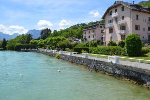 a river with ducks in the water next to buildings at Le Coin des Cygnes et le Nid du Lac, 2 appartements au bord du lac d'Annecy avec plage privée in Doussard