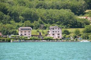 un groupe de maisons sur la rive d'une masse d'eau dans l'établissement Le Coin des Cygnes, appartement face au lac d'Annecy avec plage privée, à Doussard 19 autres photos