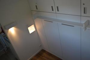 une cuisine avec des placards blancs et une lumière sur le mur. dans l'établissement Le Coin des Cygnes, appartement face au lac d'Annecy avec plage privée, à Doussard