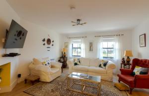 a living room with white furniture and a fireplace at Renada Cottage in Dingle