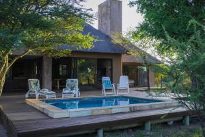 a backyard with a pool and chairs and a house at Duiker lodge in Mmukubyane