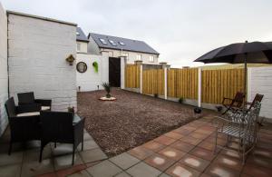 eine Terrasse mit Stühlen, einem Sonnenschirm und einem Zaun in der Unterkunft Renada Cottage in Dingle