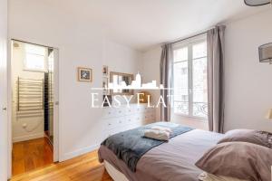 - une chambre blanche avec un lit et une fenêtre dans l'établissement Beautiful 4 - bedroom apartment near Seine River and Roland Garros, Paris 16, by Easyflat, à Paris