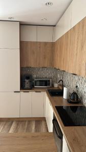 a kitchen with white cabinets and a microwave at Apartament 33 Park City in Ostrów Wielkopolski